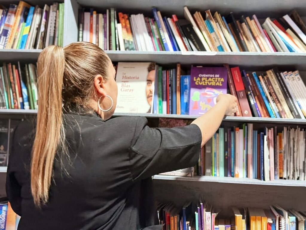 Persona acomodando los libros donados por la Secretaría Nacional de Cultura en la Biblioplaya San José, Encarnación